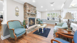 Interior Victoria Park at Edgewater lobby lounge area, stone fireplace, various seating area, wood floors with avanath floor mat, white walls.