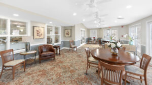 Interior Victoria Park at Edgewater dining area, rustic decor, multi-toned carpeting, leather and wood seating in room, multiple circular tables in room, various overhead fans.